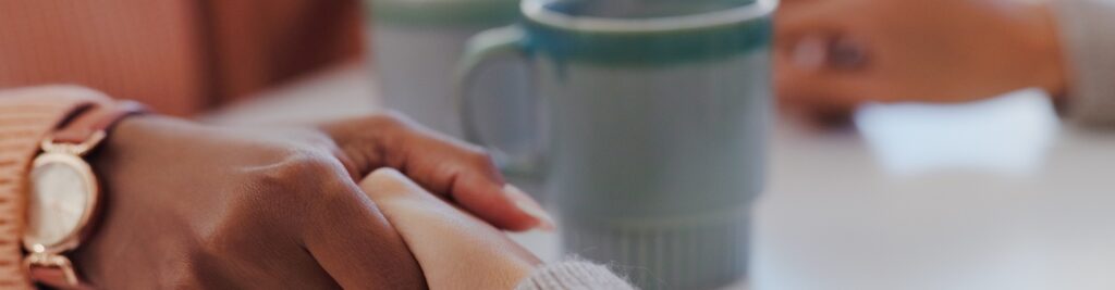 people holding hands and sharing coffee